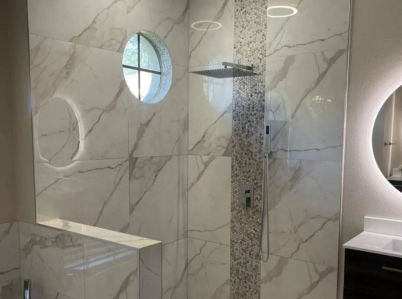 Walk-in shower in marble-look porcelain with pebble mosaic band, rain head and halo ceiling lights in Lakewood Ranch, FL