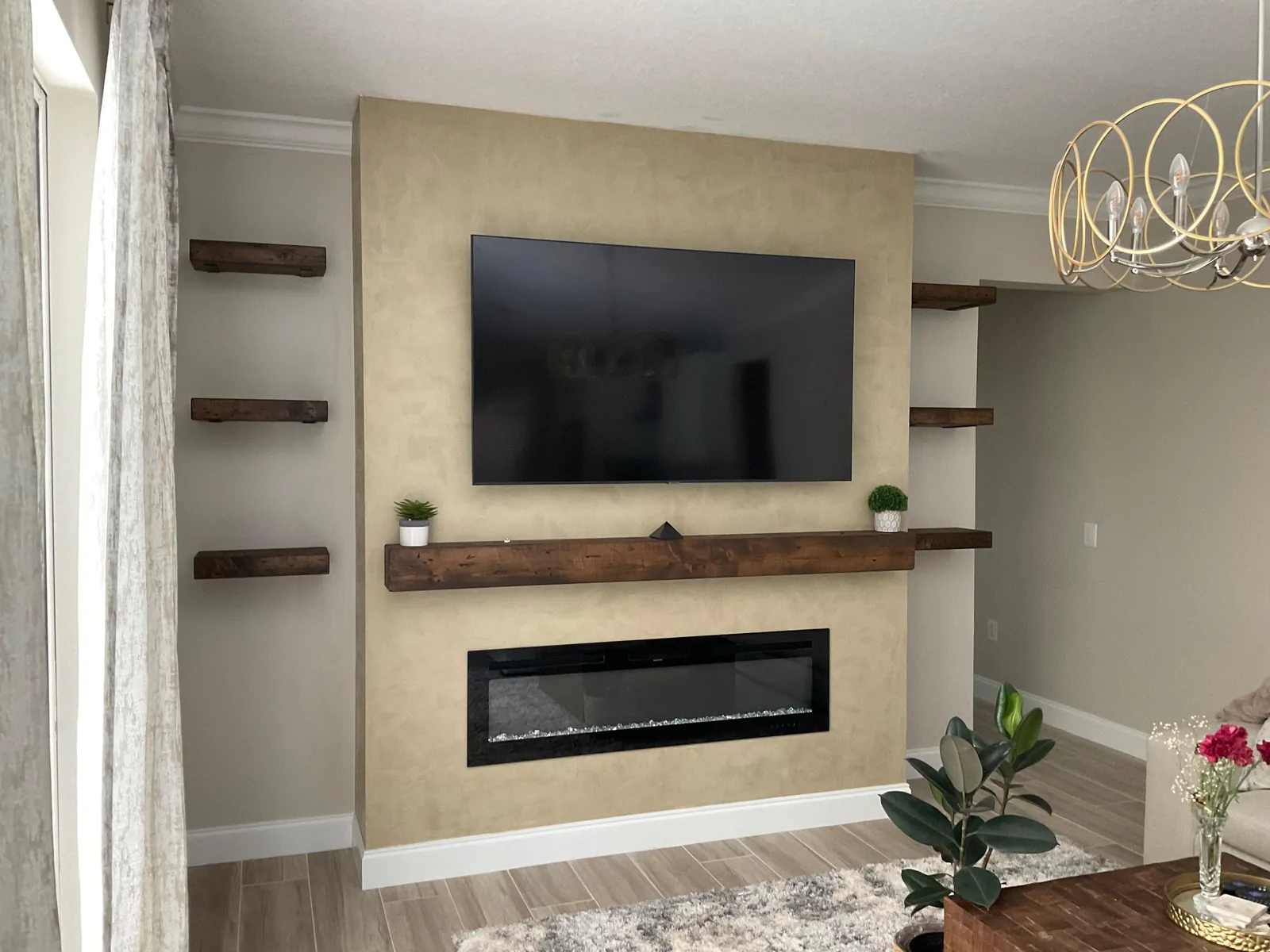 Warm beige polished plaster feature wall with wall-mounted TV, wood mantel and linear electric fireplace in Lakewood Ranch, FL