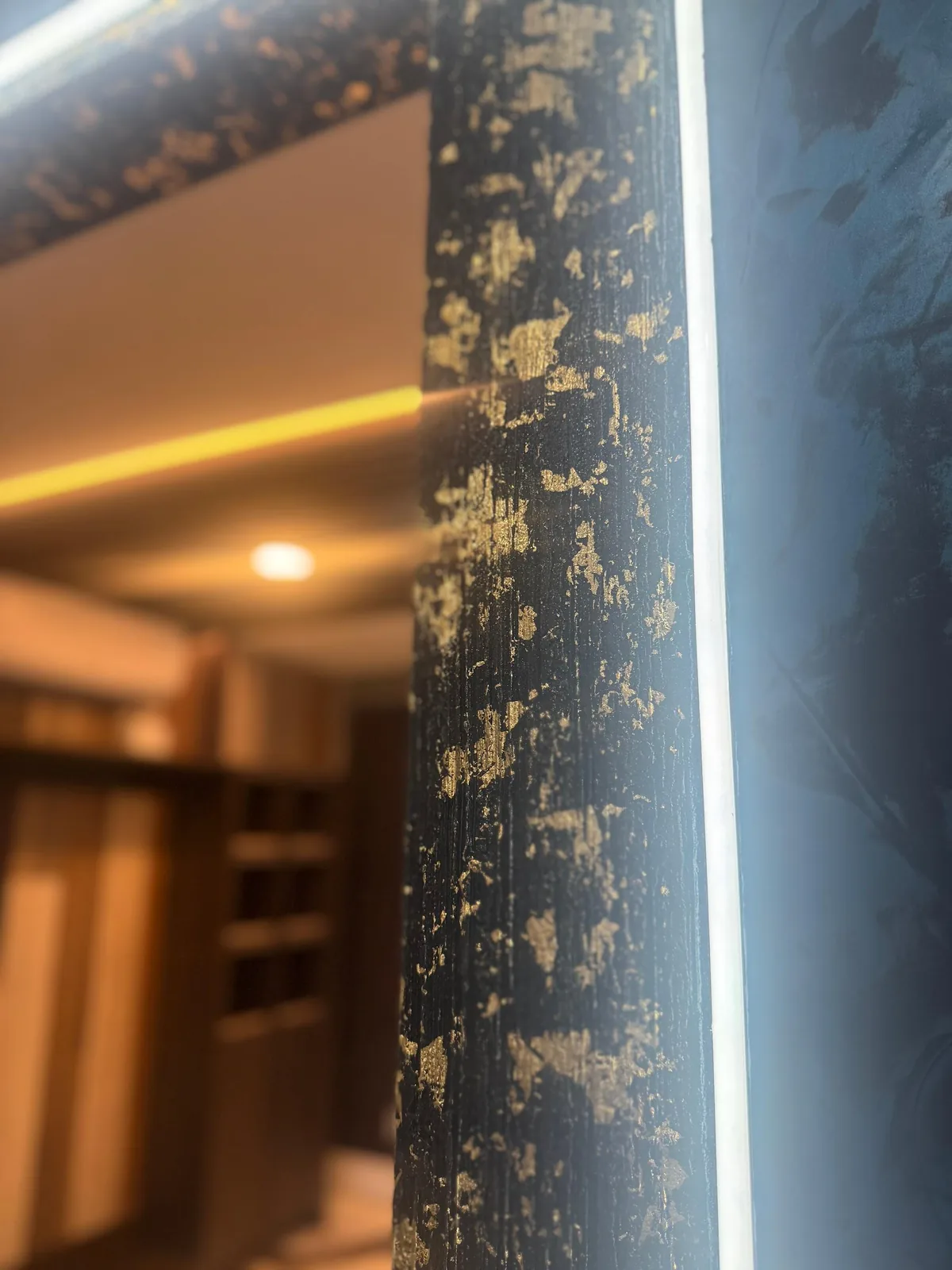 Close-up of black plaster column edge flecked with gold leaf beside LED strip lighting in Lakewood Ranch, FL