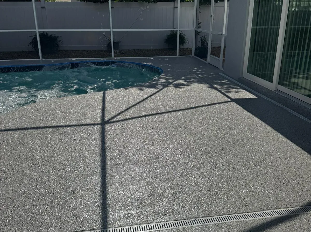 Gray flake epoxy pool deck and screened lanai with a white linear drain channel in Lakewood Ranch, FL