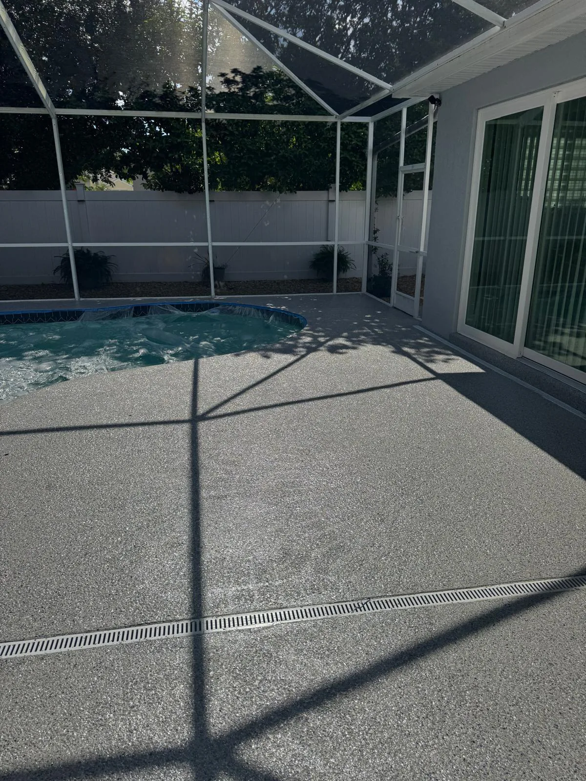 Silver gray flake epoxy deck filling a screened lanai with linear drain and sliding doors in Lakewood Ranch, FL