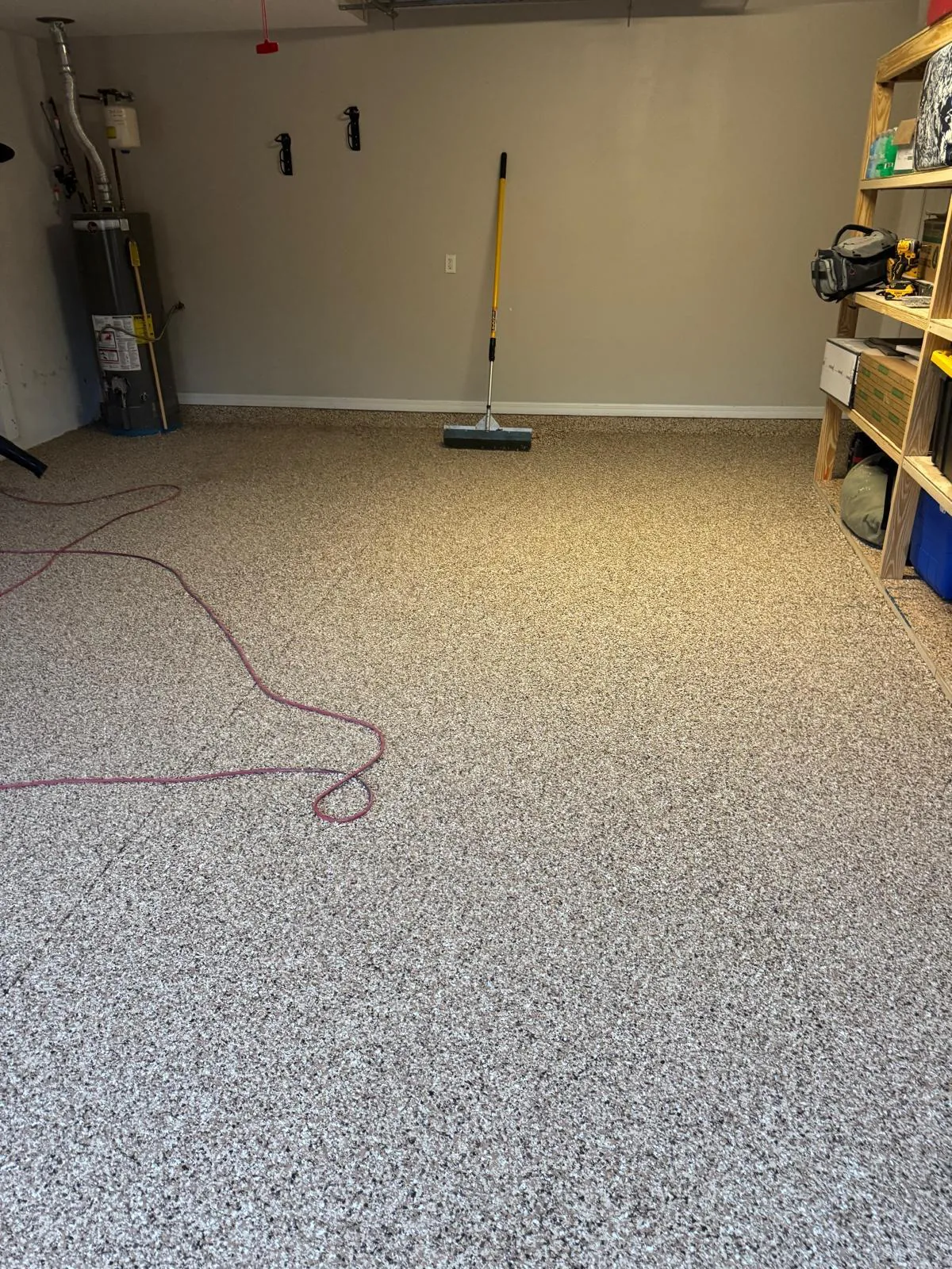 Residential garage floor coated in tan and gray flake epoxy beside water heater and shelving in Lakewood Ranch, FL