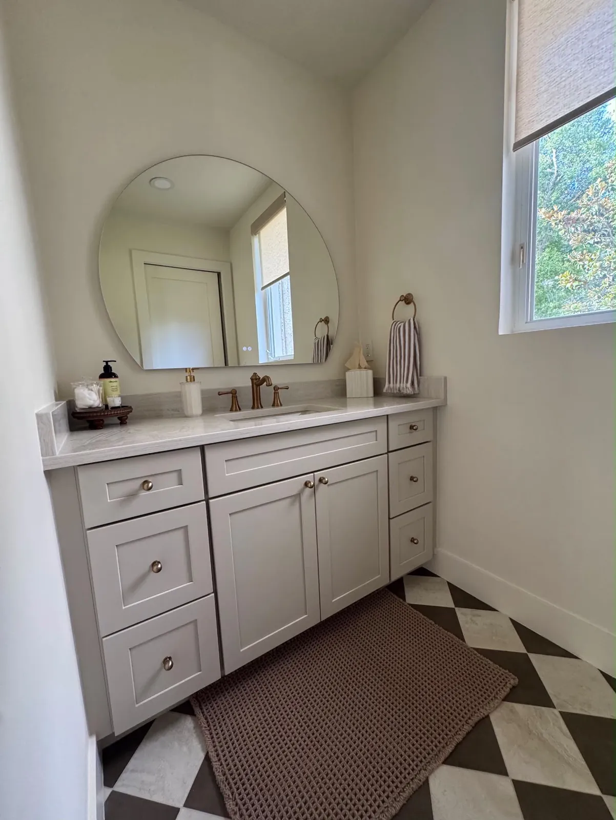 Guest bathroom remodel with shaker vanity, round mirror and checkerboard tile floor in Sarasota, FL