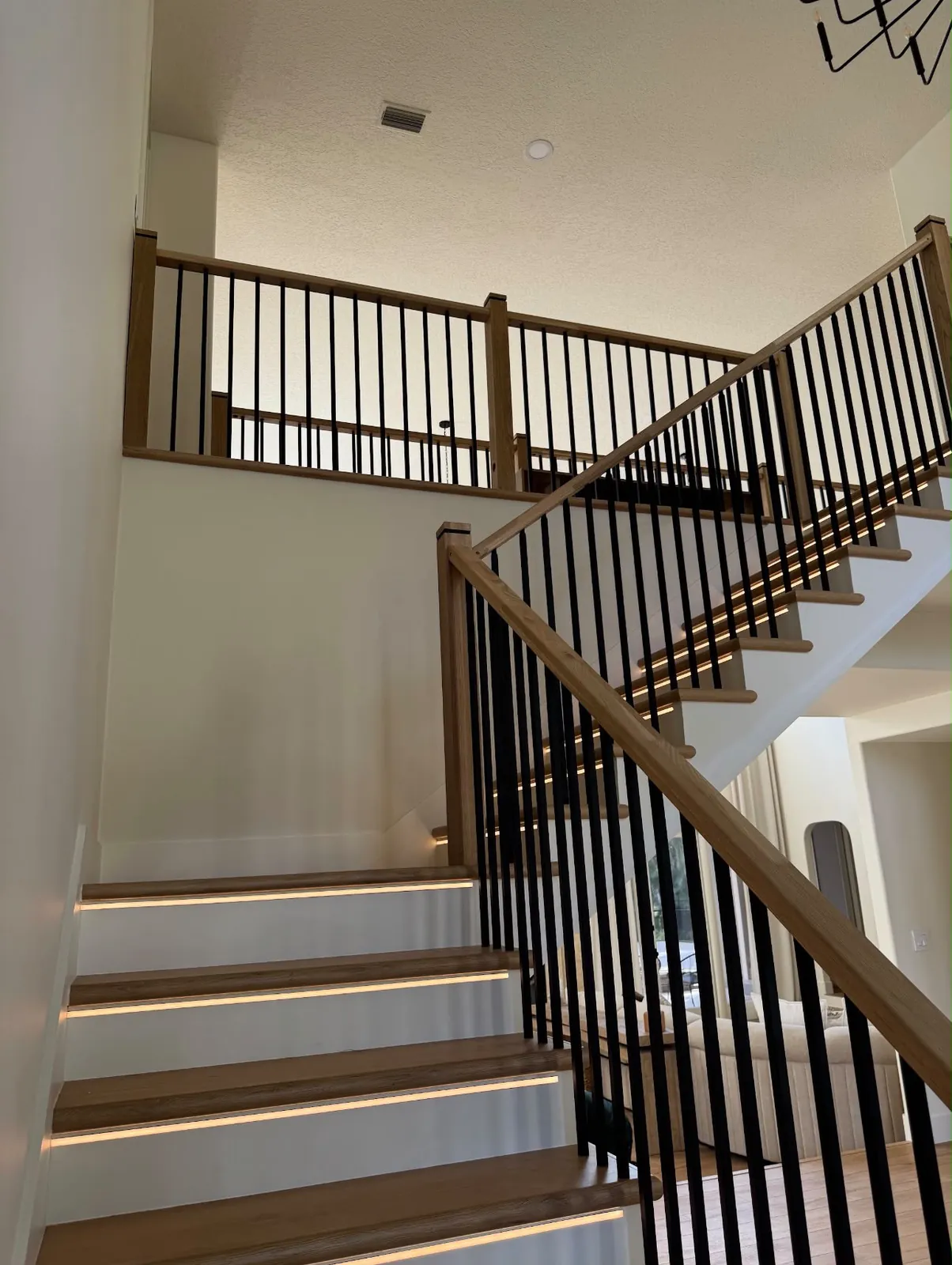 Custom oak staircase with black metal balusters and LED-lit treads