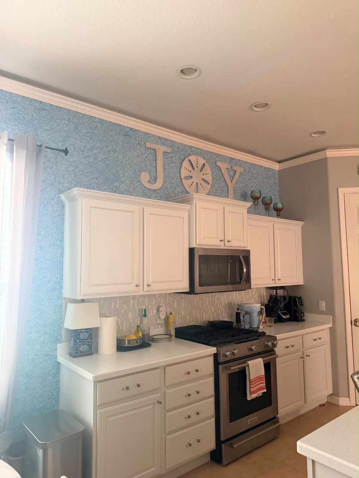 Liquid wallpaper silk plaster accent wall in a white coastal kitchen