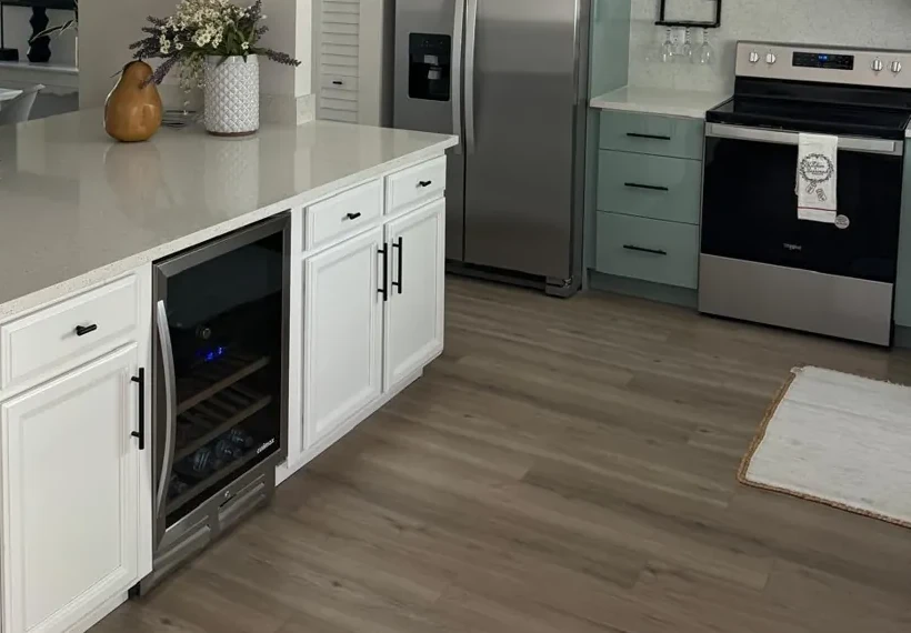White painted peninsula cabinets with black pulls beside mint green base cabinets and stainless range in Lakewood Ranch, FL