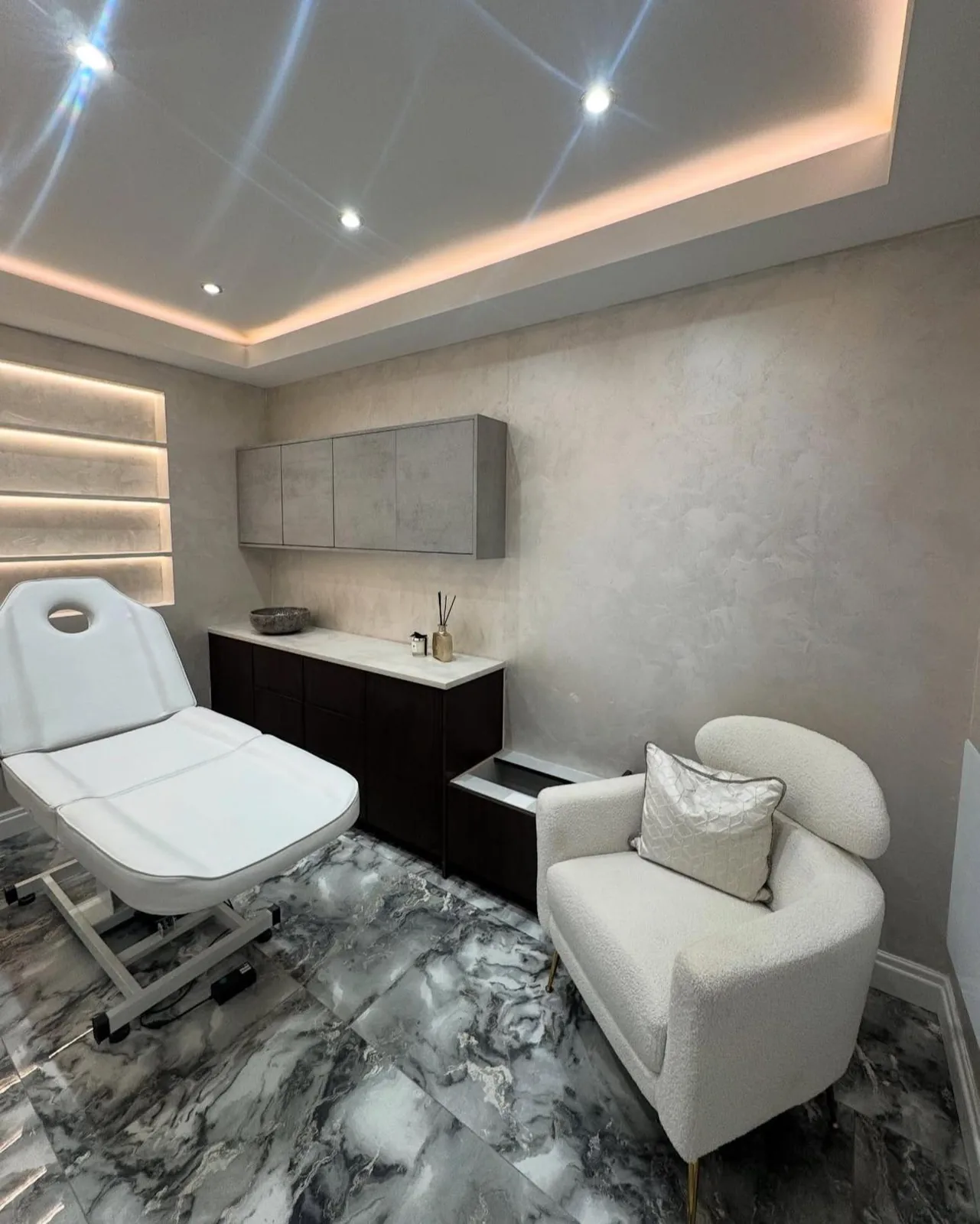Treatment room with soft gray polished mineral wall finish, cove lighting and marble-look floor in Lakewood Ranch, FL