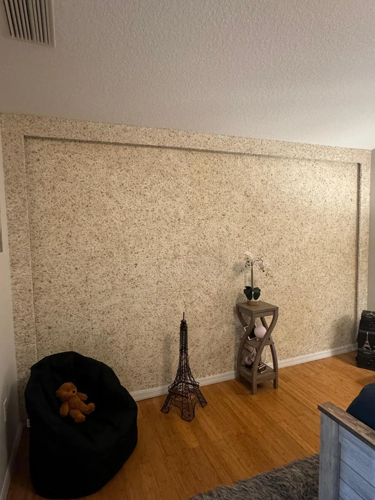 Beige flecked wall panel with a recessed rectangular border above honey toned wood flooring in Lakewood Ranch, FL