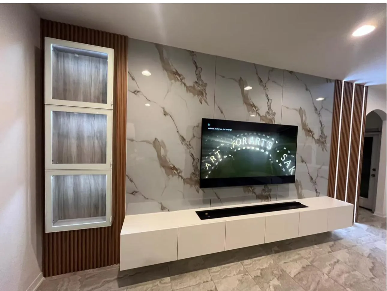 Calacatta marble-look panel TV wall with wood slat columns, backlit niches and floating white cabinet in Lakewood Ranch, FL