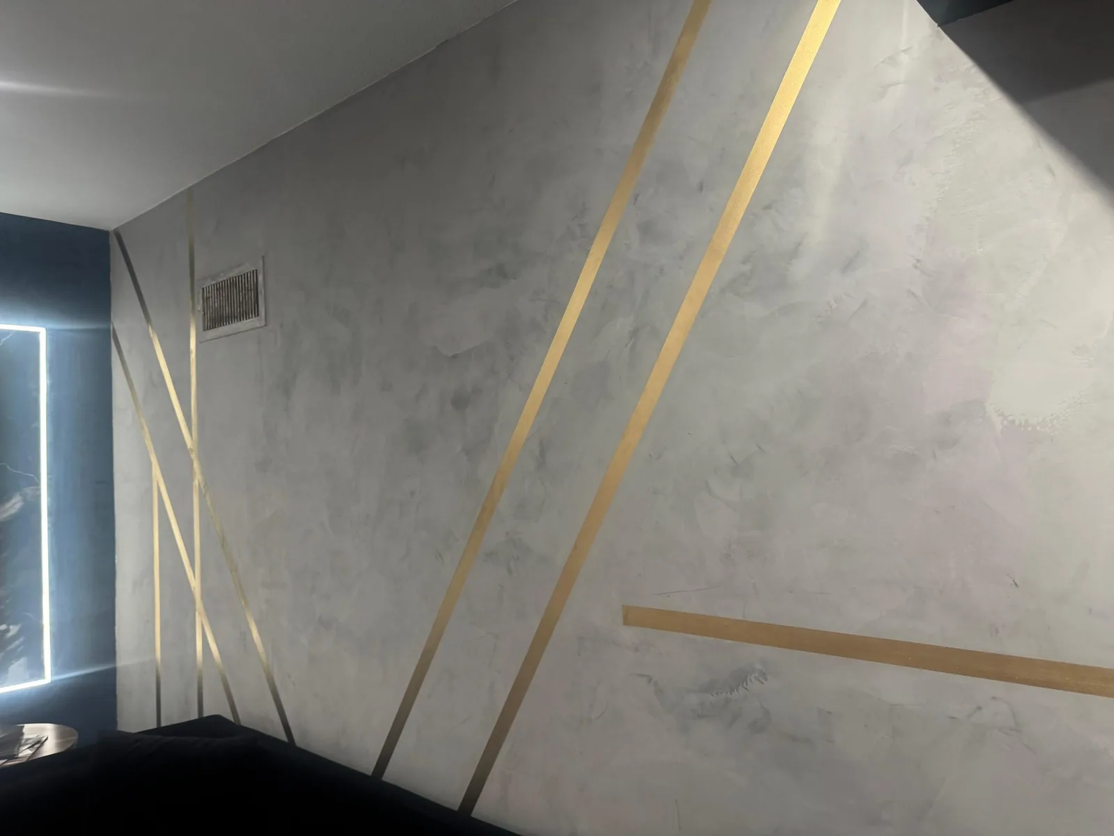 Off-white polished plaster wall with wide brass inlay stripes meeting a deep blue plaster corner in Lakewood Ranch, FL