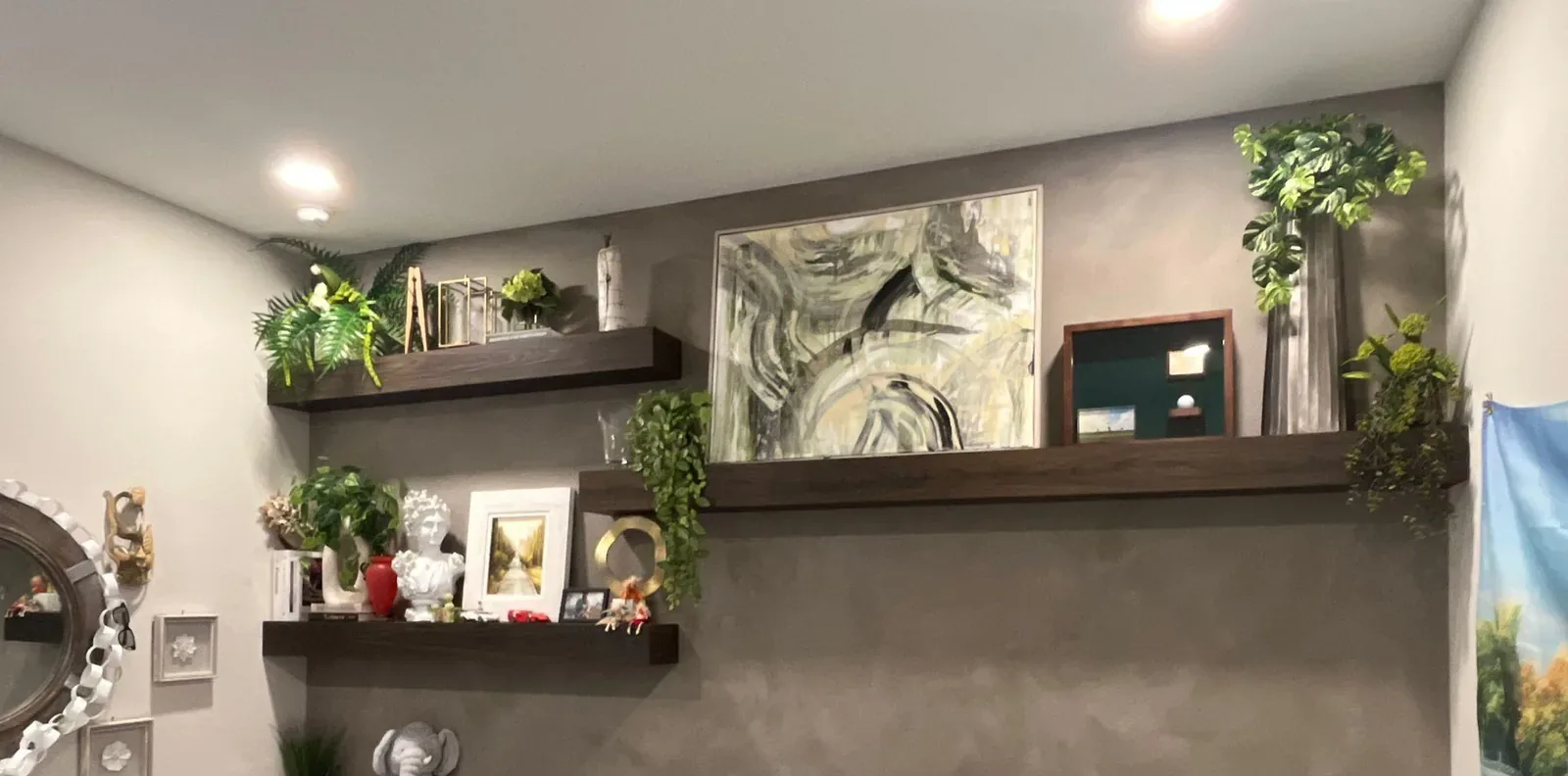 Deep taupe velvet-finish accent wall with dark floating shelves, framed art and trailing plants in Lakewood Ranch, FL
