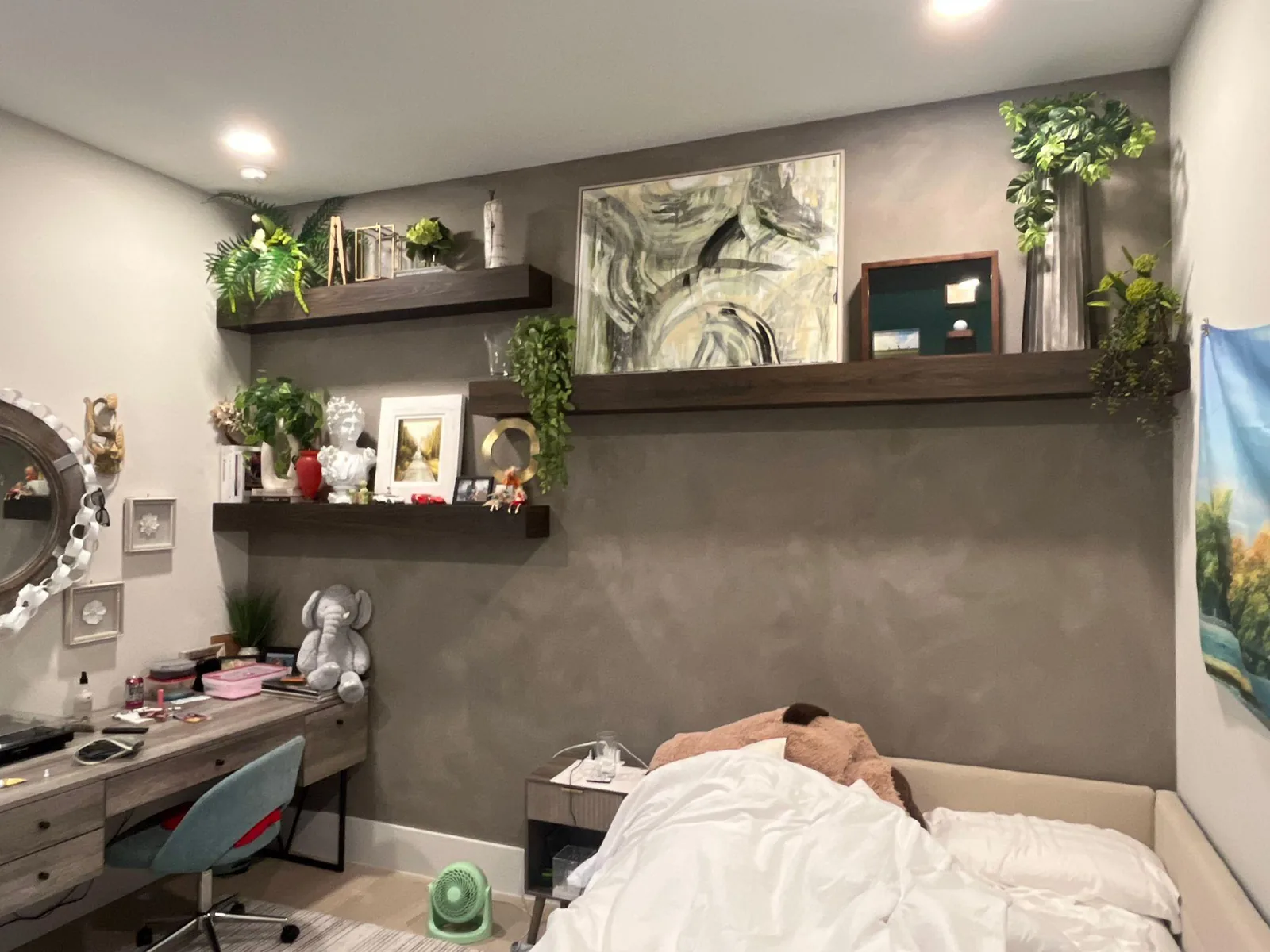 Bedroom with taupe velvet accent wall, dark floating shelves, framed art, and desk area in Lakewood Ranch, FL
