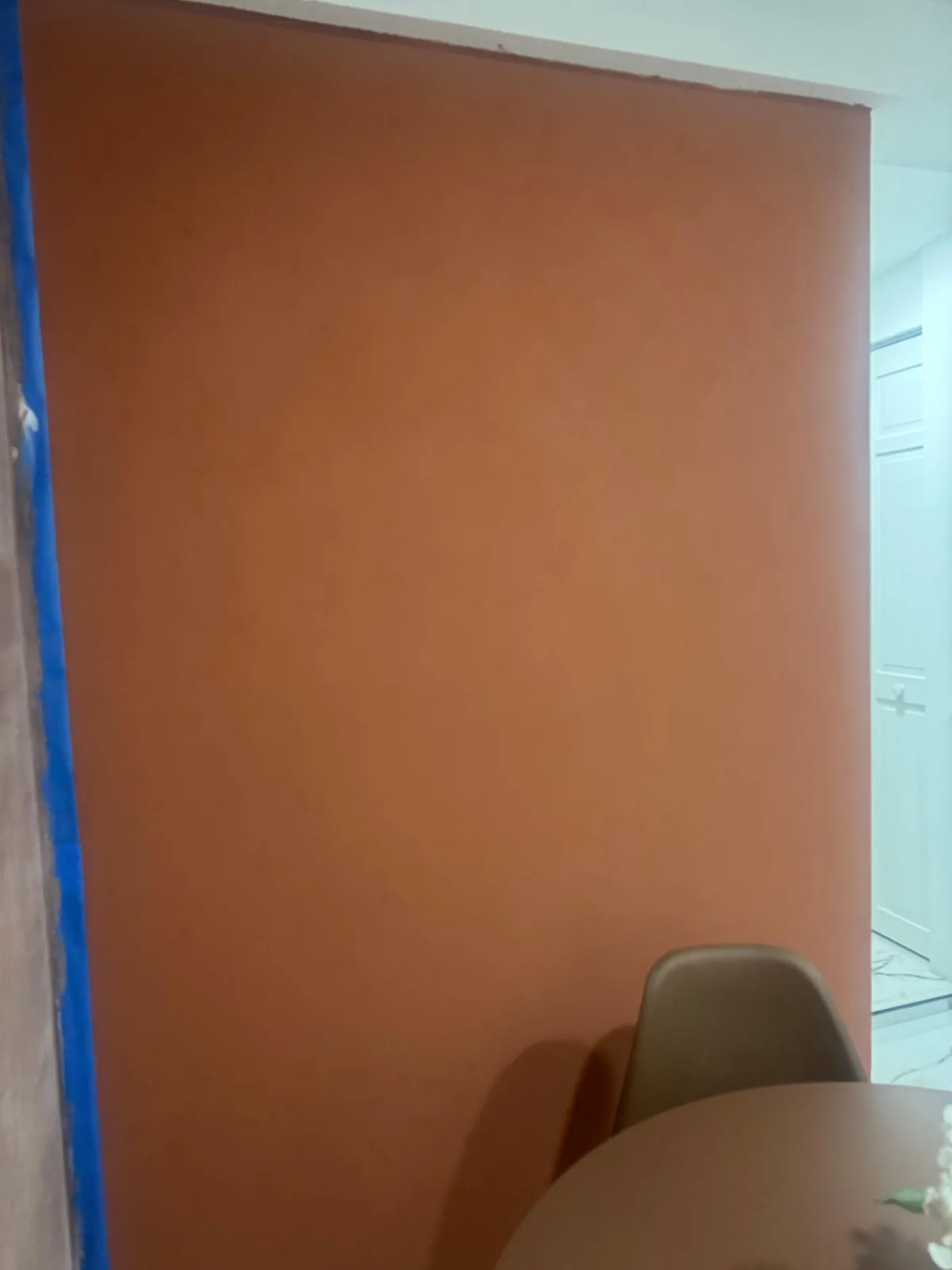 Terracotta painted wall with blue painters tape still masking the adjoining white wall in Lakewood Ranch, FL