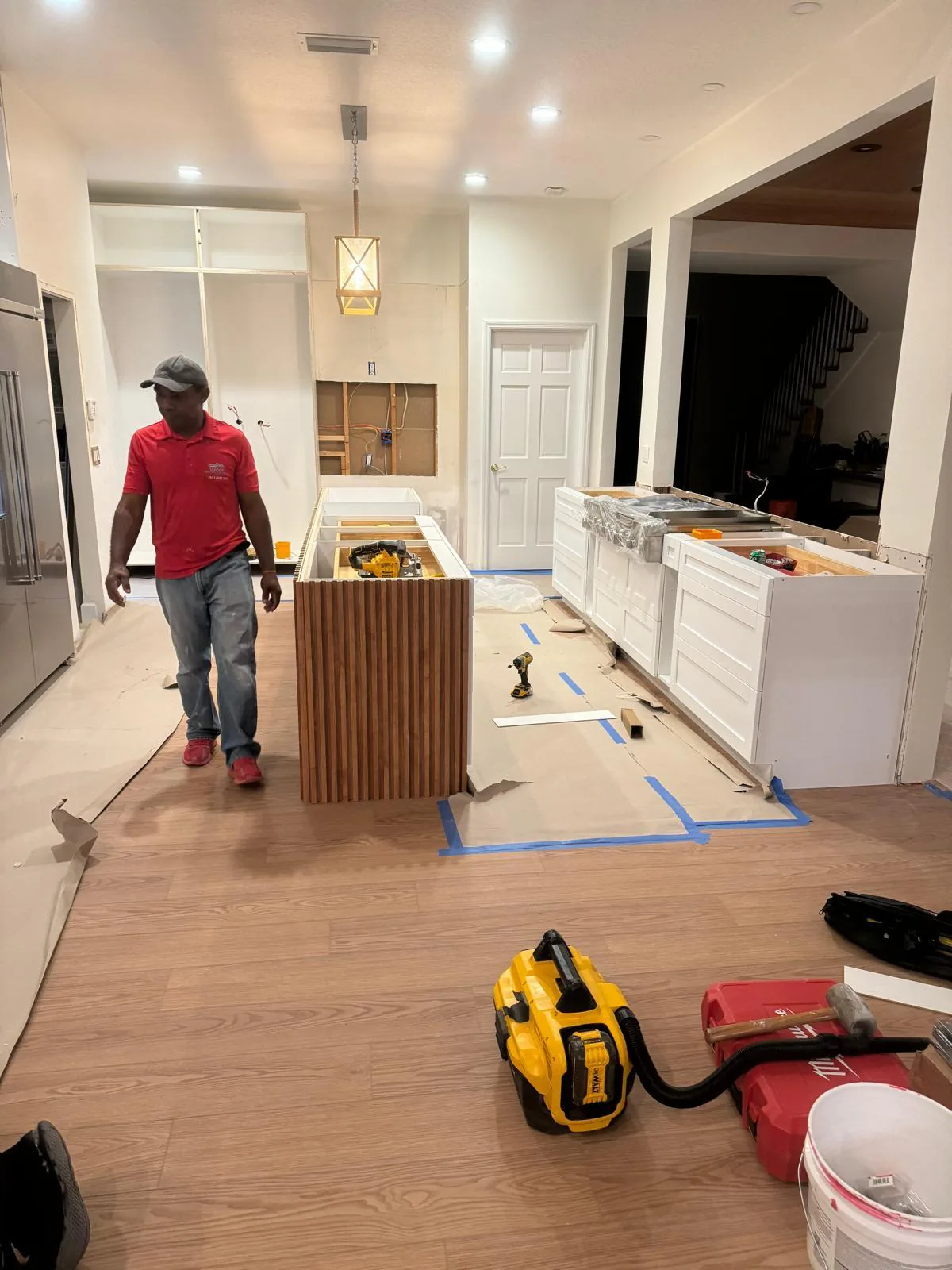 Crew member in a red company polo walking through a kitchen under construction with tools in Lakewood Ranch, FL