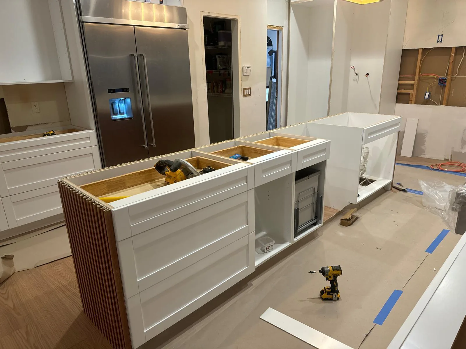 White cabinet boxes being installed on a new kitchen island beside a stainless refrigerator in Lakewood Ranch, FL