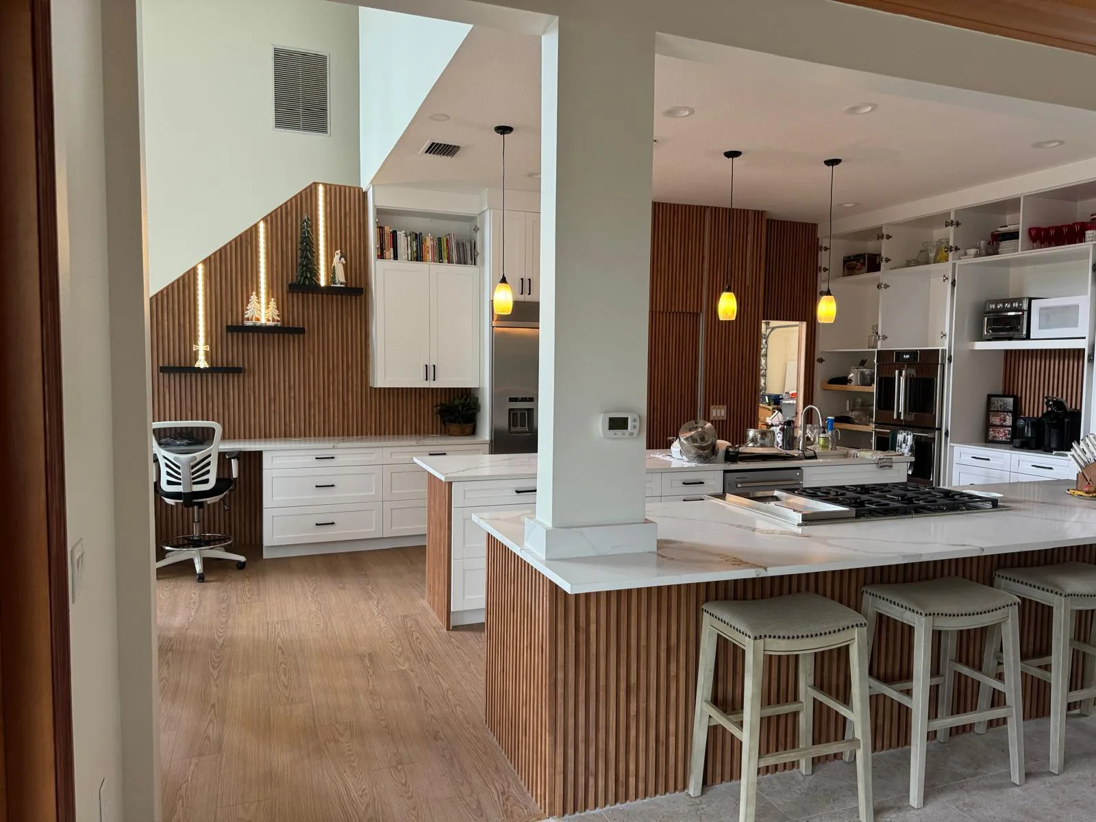 Remodeled kitchen with white cabinetry, built-in desk, floating shelves and fluted wood wall panels in Lakewood Ranch, FL