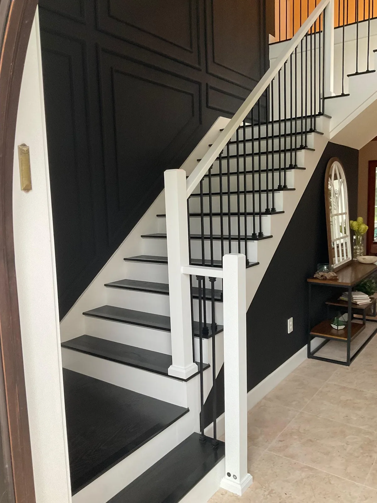 Finished staircase with black paneled accent wall, white risers, dark treads and iron balusters in Sarasota, FL
