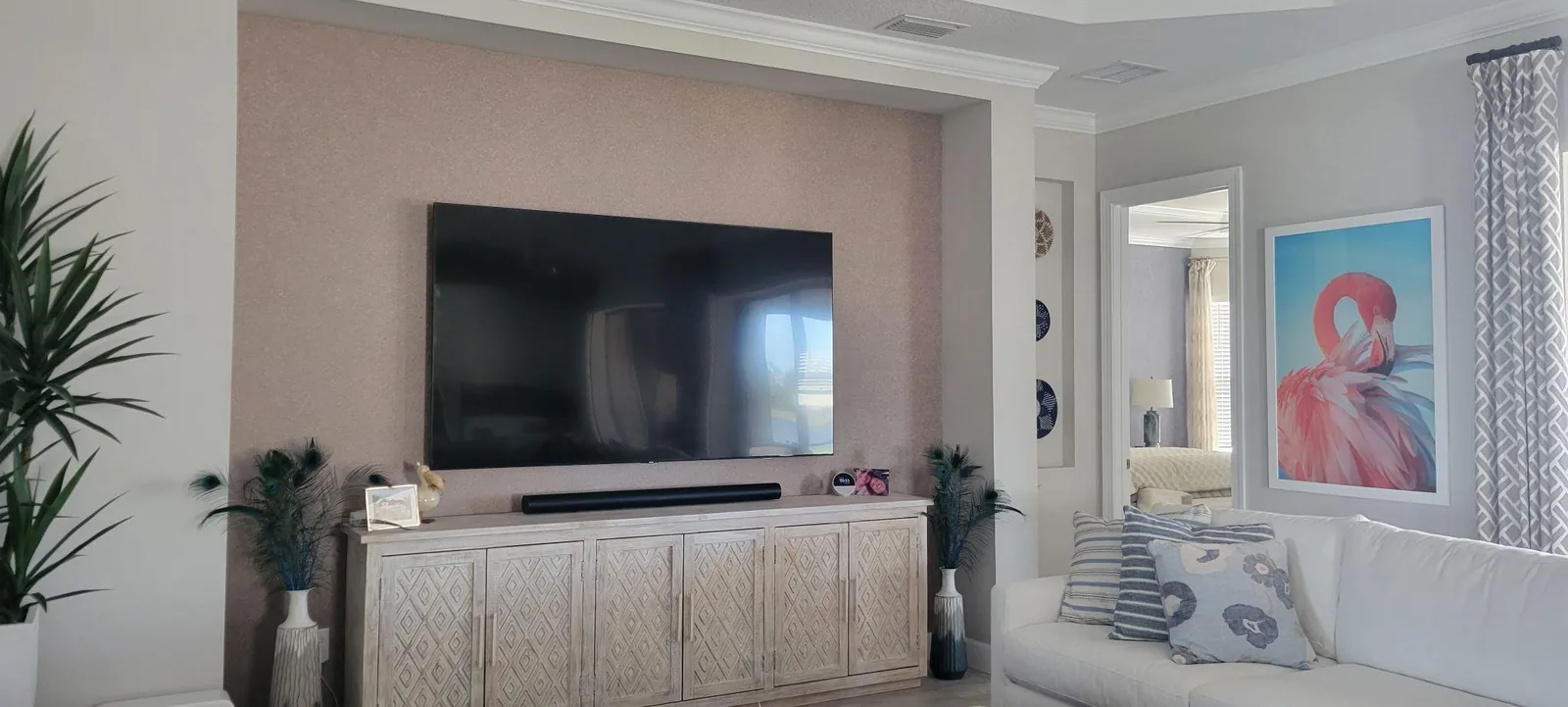 Rose-taupe fine-textured plaster accent wall behind a wall-mounted TV and carved whitewashed console in Lakewood Ranch, FL