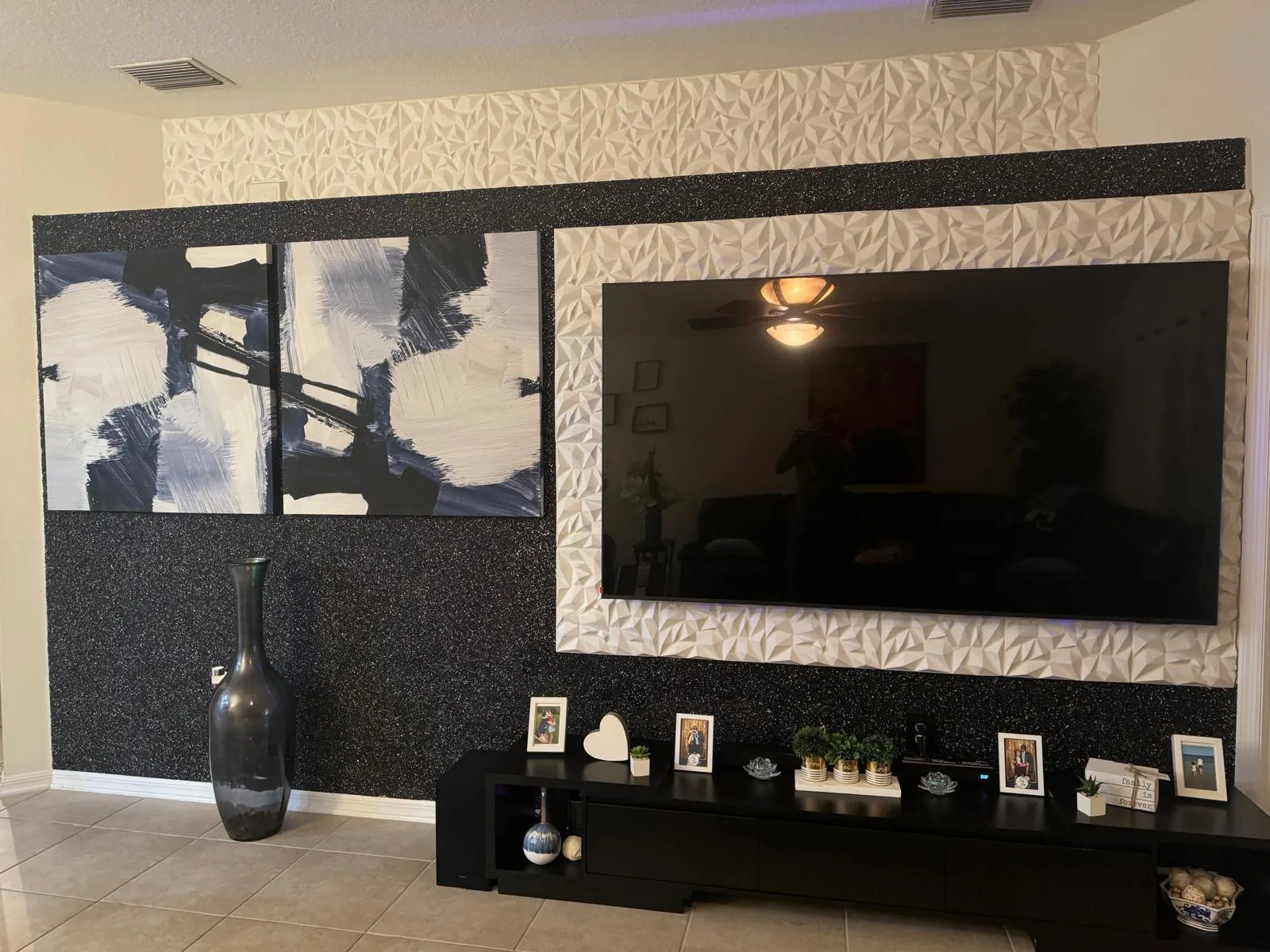 Media wall with black sparkle plaster finish and white three-dimensional panels framing a large television in Lakewood Ranch, FL