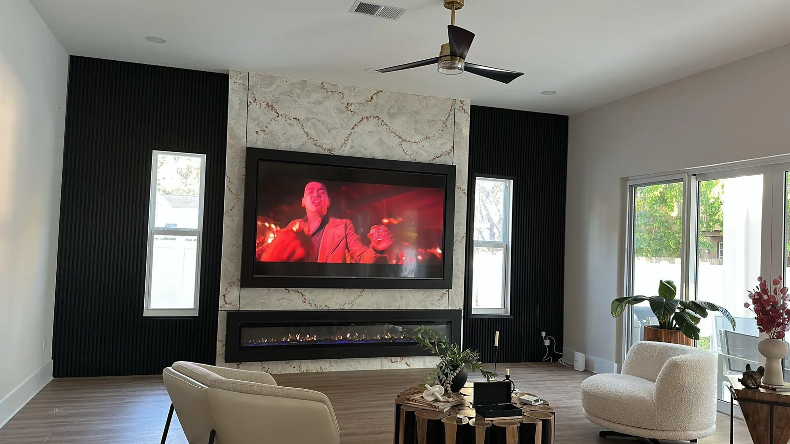 Living room with black fluted slat walls flanking a marble-look panel fireplace wall and TV in Sarasota, FL