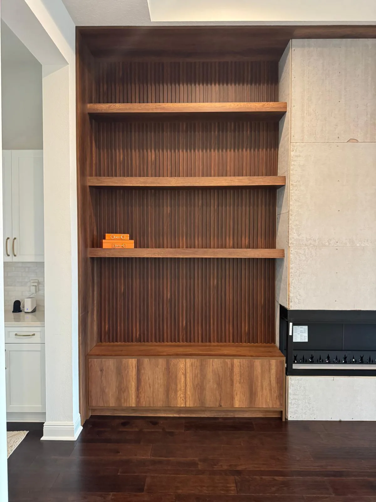 Dark wood-tone built-in with floating shelves, fluted slat back panel and closed base cabinet in Lakewood Ranch, FL