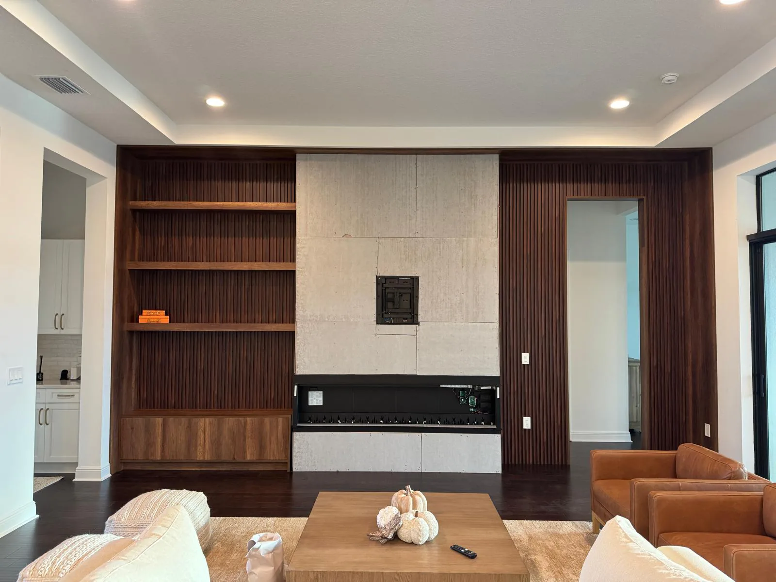 Living room wall of walnut built-in shelving and slat paneling flanking a linear fireplace in Lakewood Ranch, FL